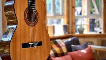 Una chitarra appesa al muro in una stanza con una finestra, un divano con dei cuscini e un tavolino.