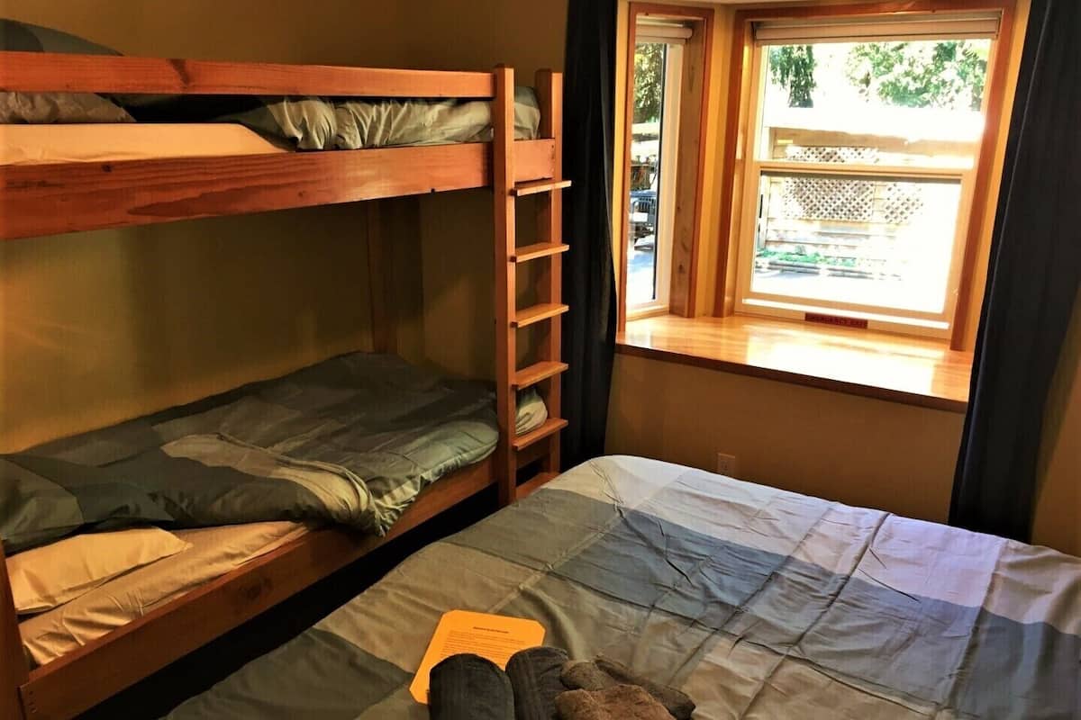 Een slaapkamer met stapelbed, raam en een ladder.