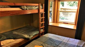Een slaapkamer met stapelbed, raam en een ladder.