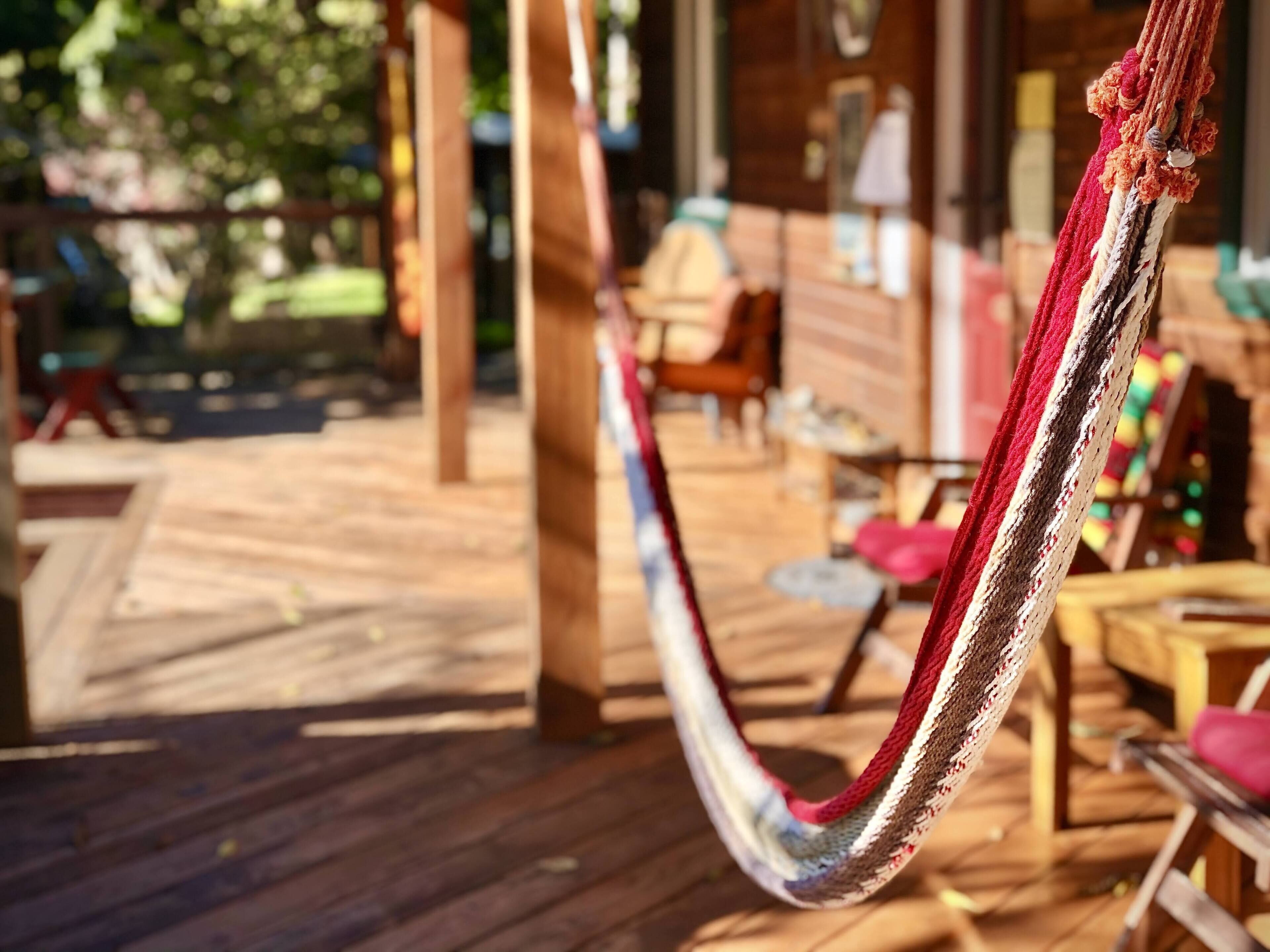 A hammock hanging between wooden posts on a wooden deck.