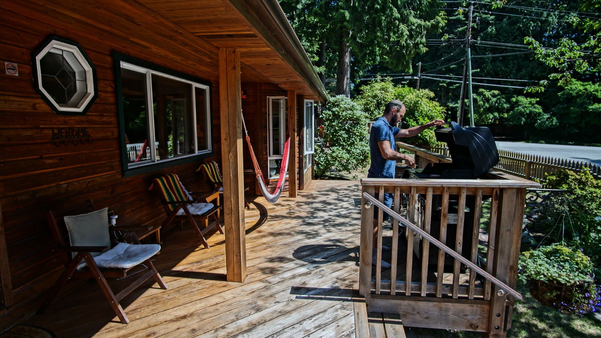 Une cabane en bois dotée d’une véranda, d’un espace salon extérieur et d’un coin barbecue.