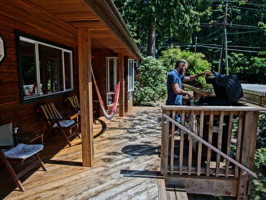 Une cabane en bois dotée d’une véranda, d’un espace salon extérieur et d’un coin barbecue.