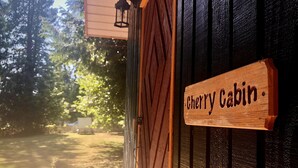 Une pancarte en bois portant l’inscription « Cherry Cabin » est fixée à la façade d’un bâtiment.