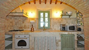 Una cocina con arco de ladrillo, una ventana, una estufa, un microondas y un armario.