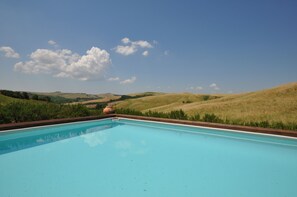 A swimming pool with a clear view of rolling hills and a blue sky.