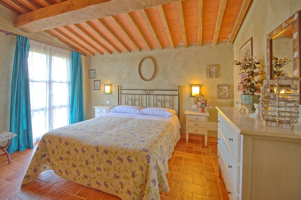 Un dormitorio con cama, mesitas de noche, cómoda y espejo.