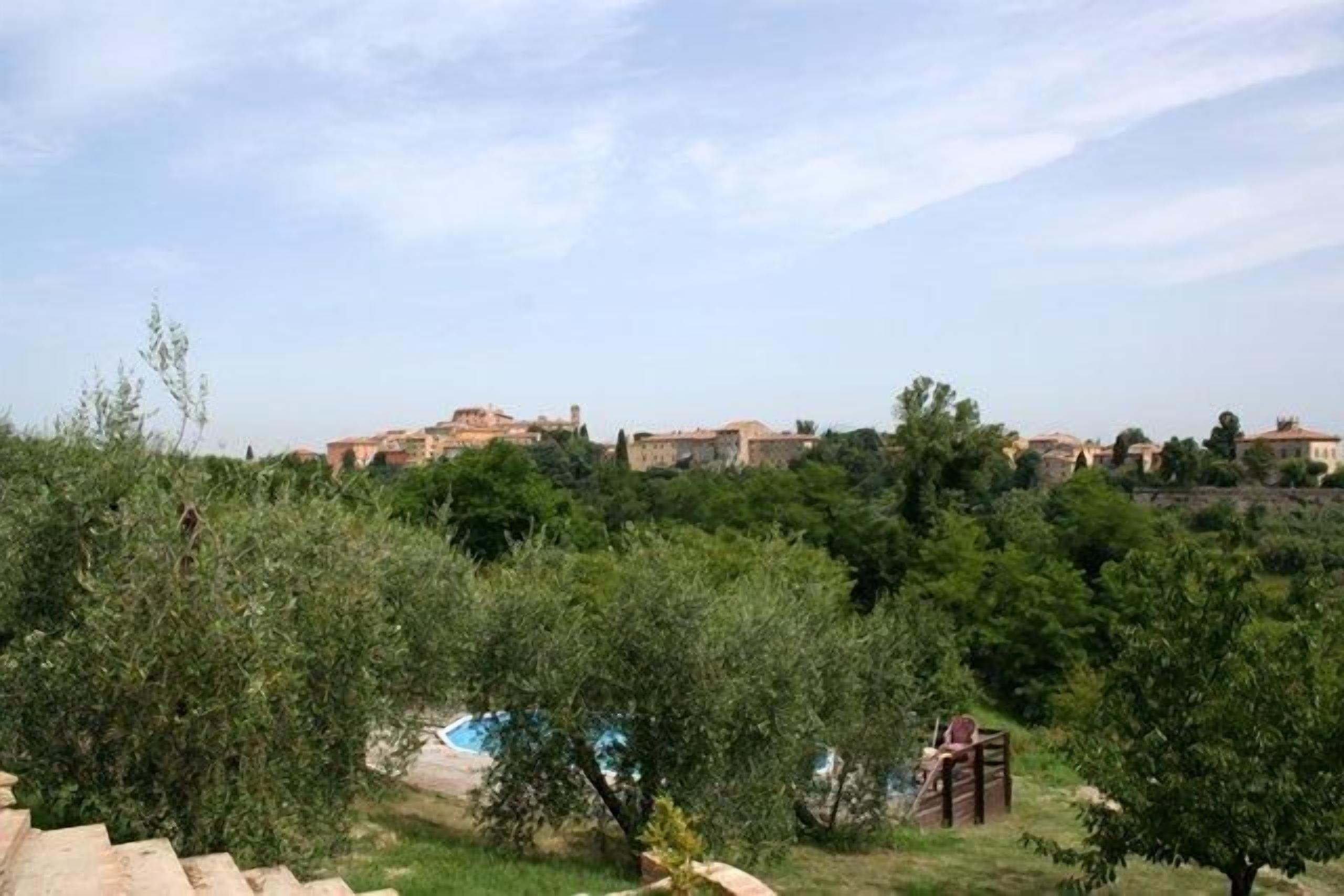 Un quartier résidentiel doté d’une piscine entourée d’arbres, offrant une vue sur des bâtiments situés au loin.