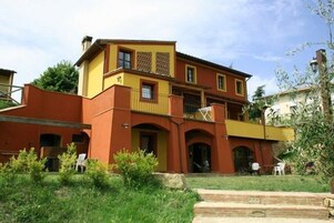 Un edificio a due piani con facciata giallo e rossa, con un balcone e porte ad arco.
