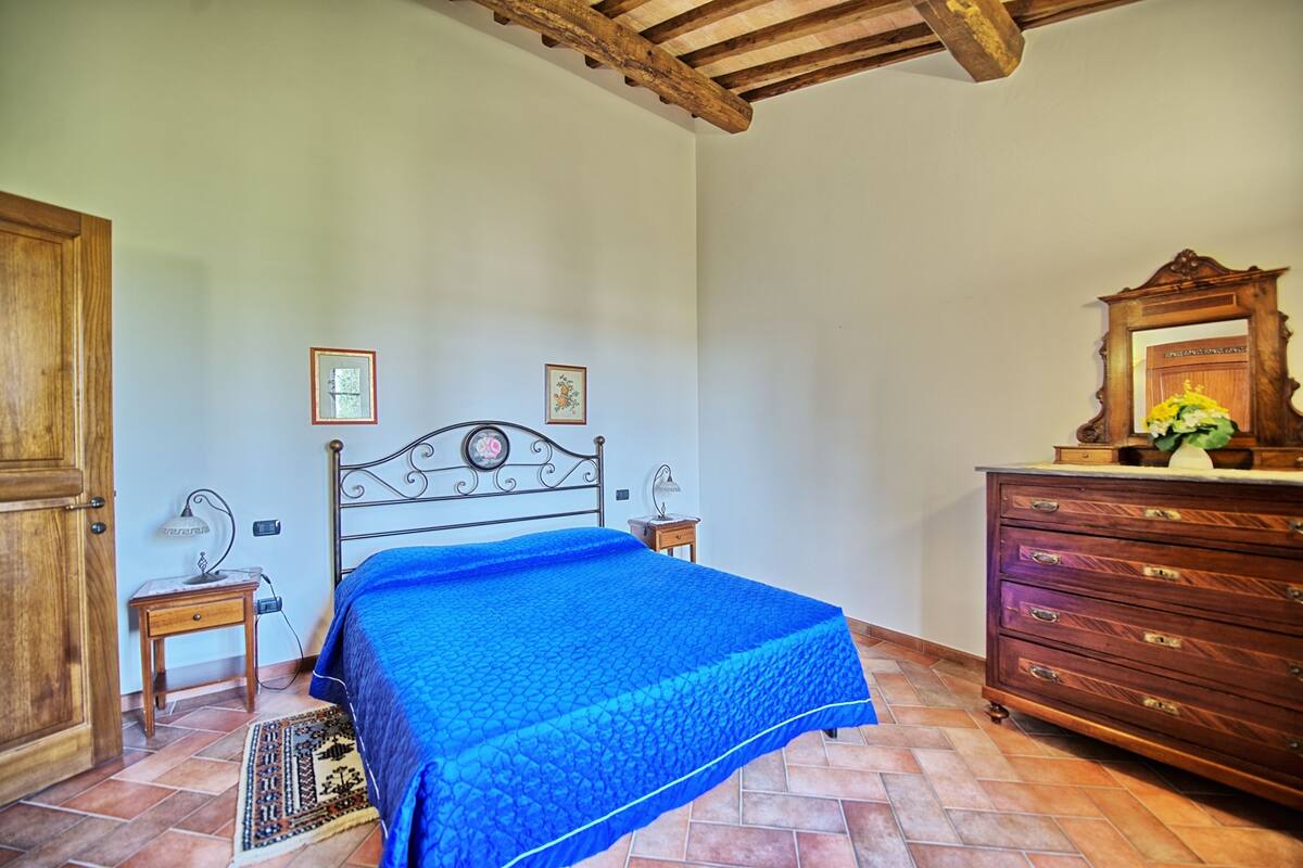 A bedroom with a bed, wooden dresser, and a wooden ceiling.