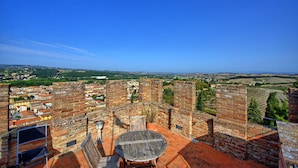A rooftop terrace with a round table and chairs, surrounded by brick walls, overlooking a cityscape and countryside. - Certaldo (Certaldo)