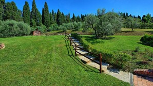 A grassy field with a stone pathway leading to a small wooden cabin. - Villa Nora (Empoli)