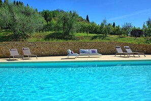 Un espace aménagé au bord de la piscine, avec des chaises longues et un mur en pierre.