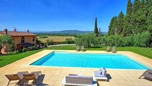 A swimming pool with lounge chairs, a house with a tiled roof, and a view of the countryside. - Villa Nora (Empoli)