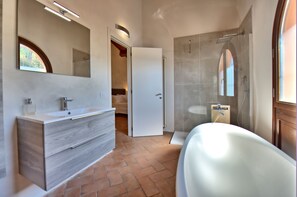 Une salle de bain moderne avec une grande baignoire, un meuble-lavabo avec un miroir et un espace douche.