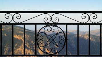 A balcony with a wrought iron railing and a view of a mountainous landscape.