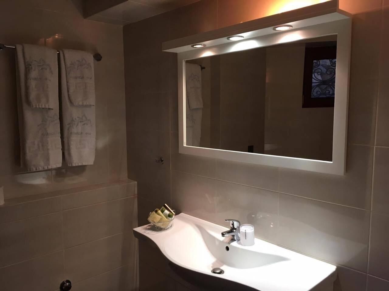 Een badkamer met een wit wastafel, een spiegel, en twee handdoeken aan de muur.