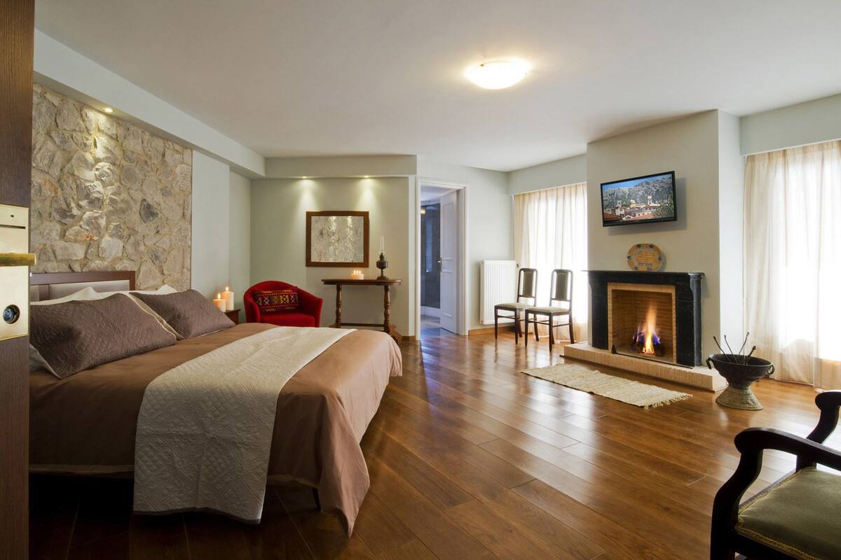 Une pièce spacieuse avec un grand lit, une cheminée et un mur en pierre décoratif.