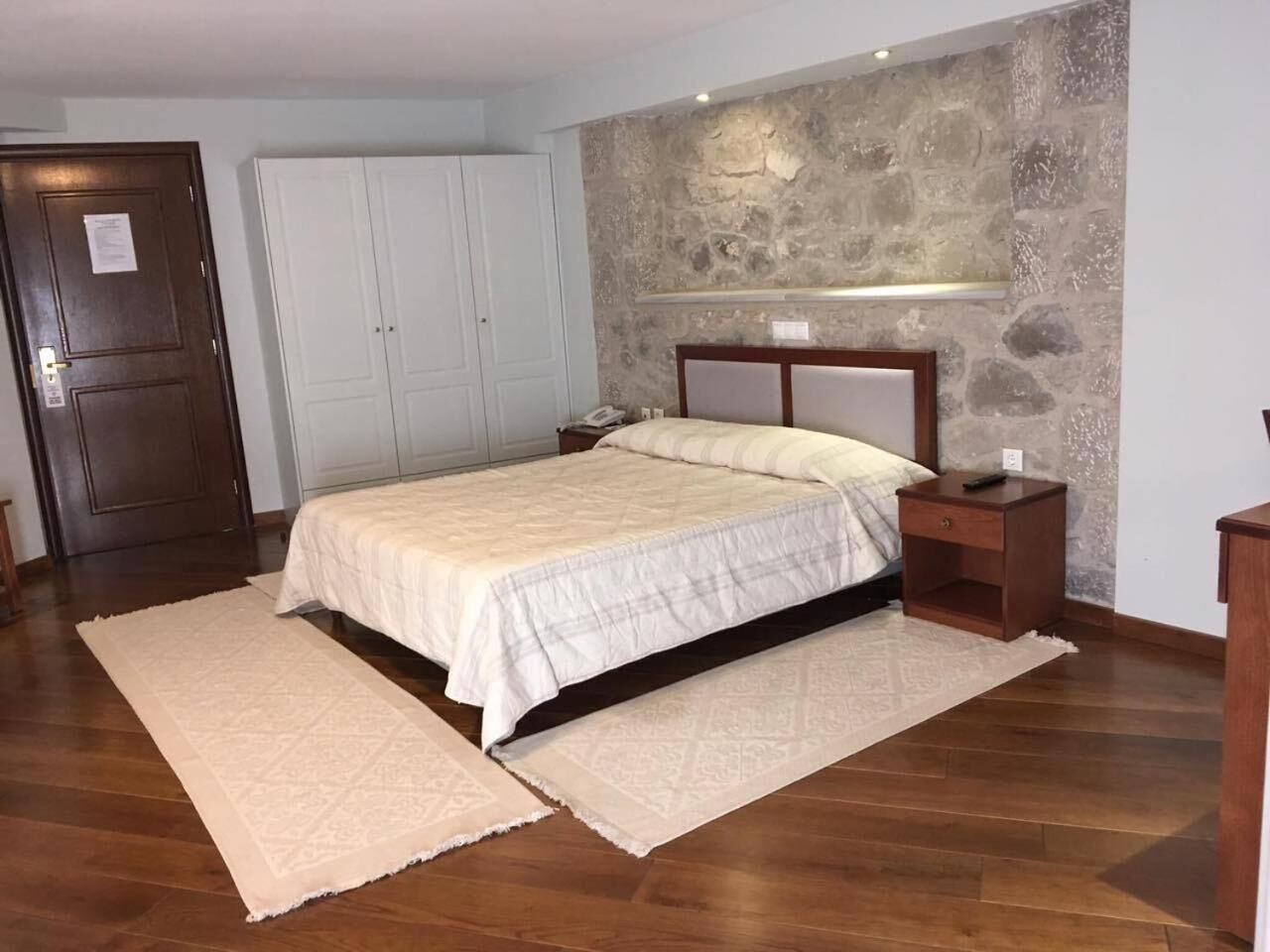 Ein Schlafzimmer mit Bett, Nachttisch und einer Steinwand.