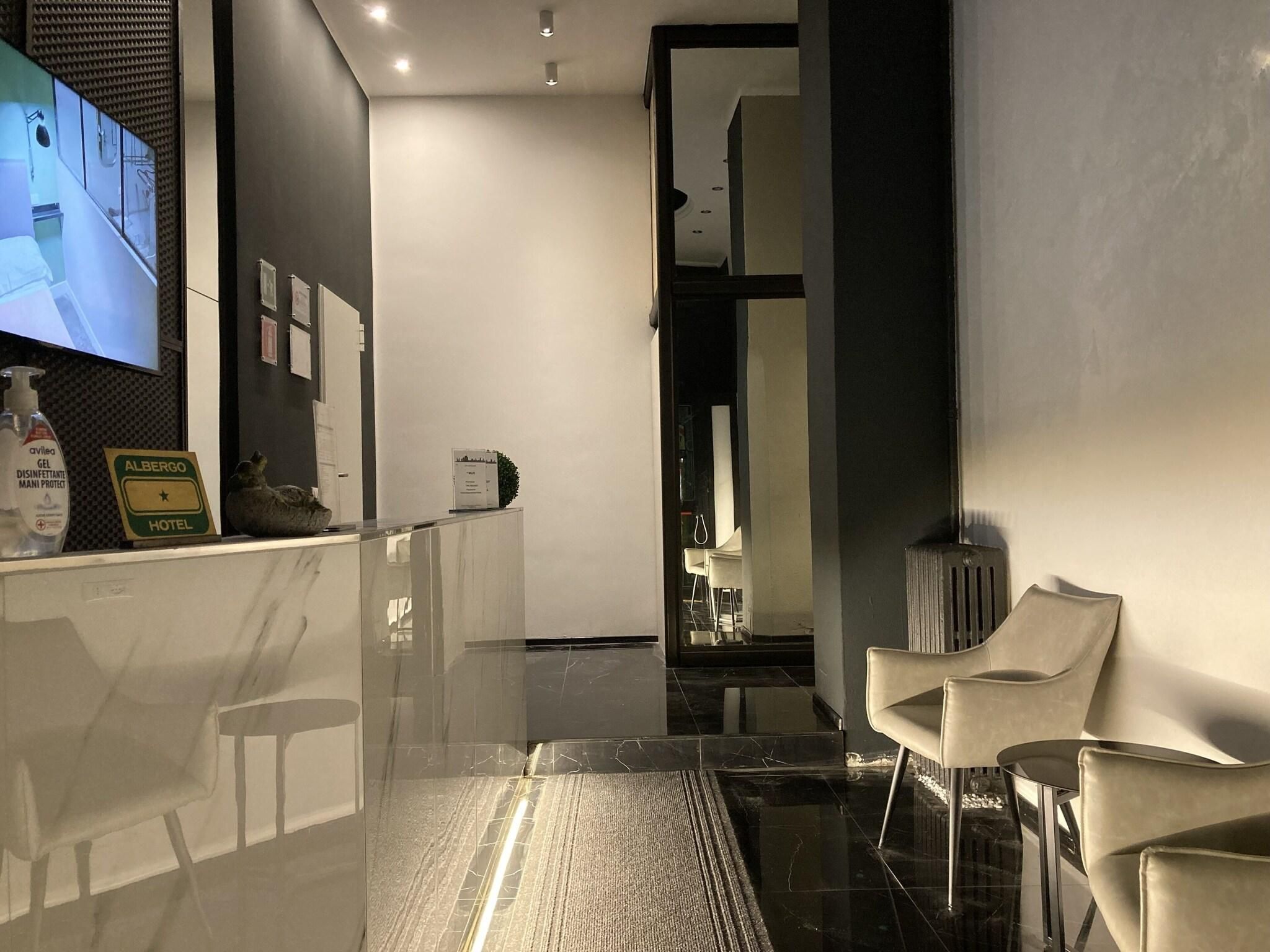 A modern hotel lobby with a reception desk, a television, and a seating area.