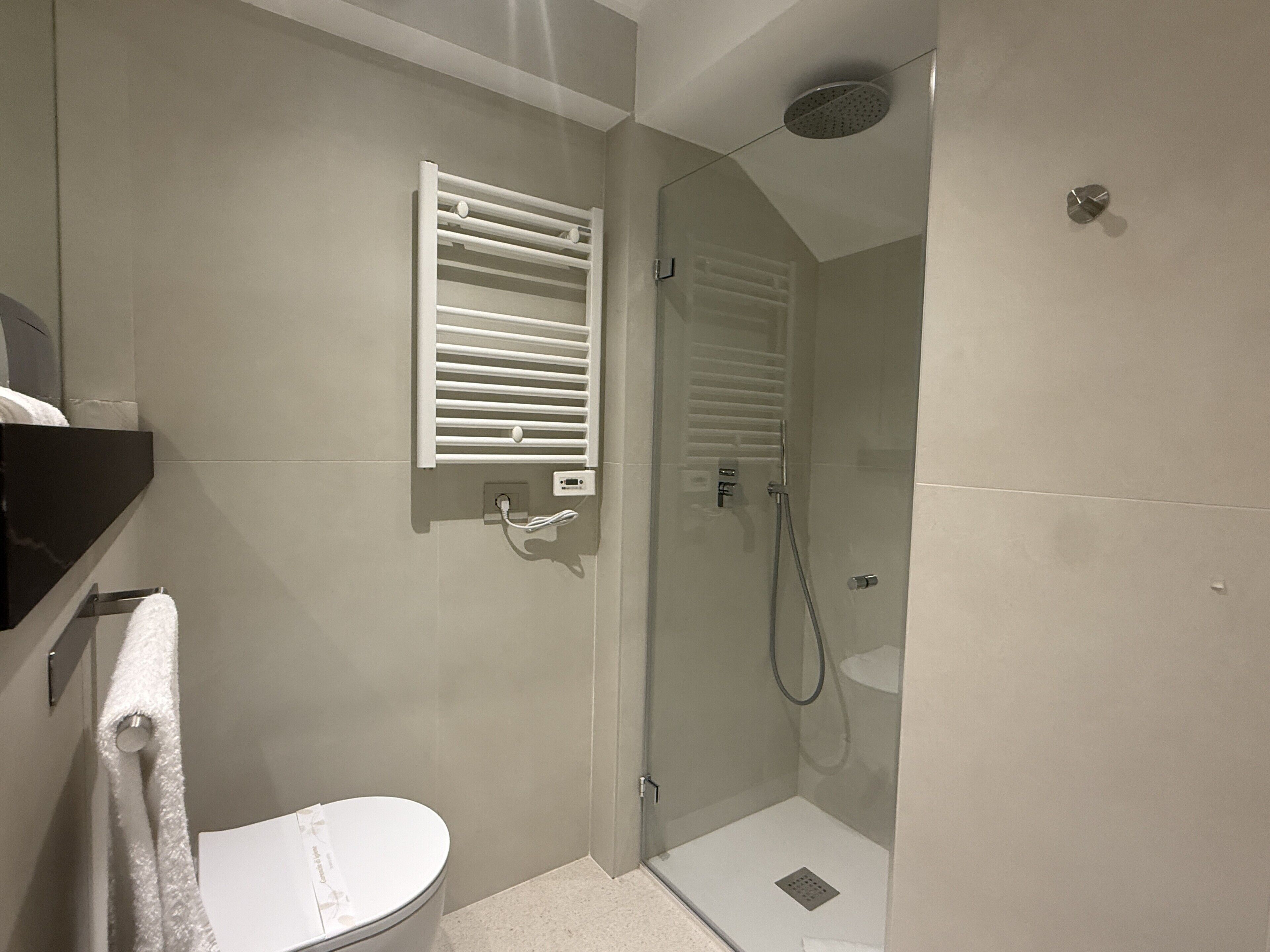 A bathroom with a toilet, a shower enclosure, and a towel rack.