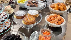 Noutopöytä, jossa on tarjolla monenlaista ruokaa, kuten hedelmiä, leivonnaisia ja erilaisia kastikkeita ja mausteita.