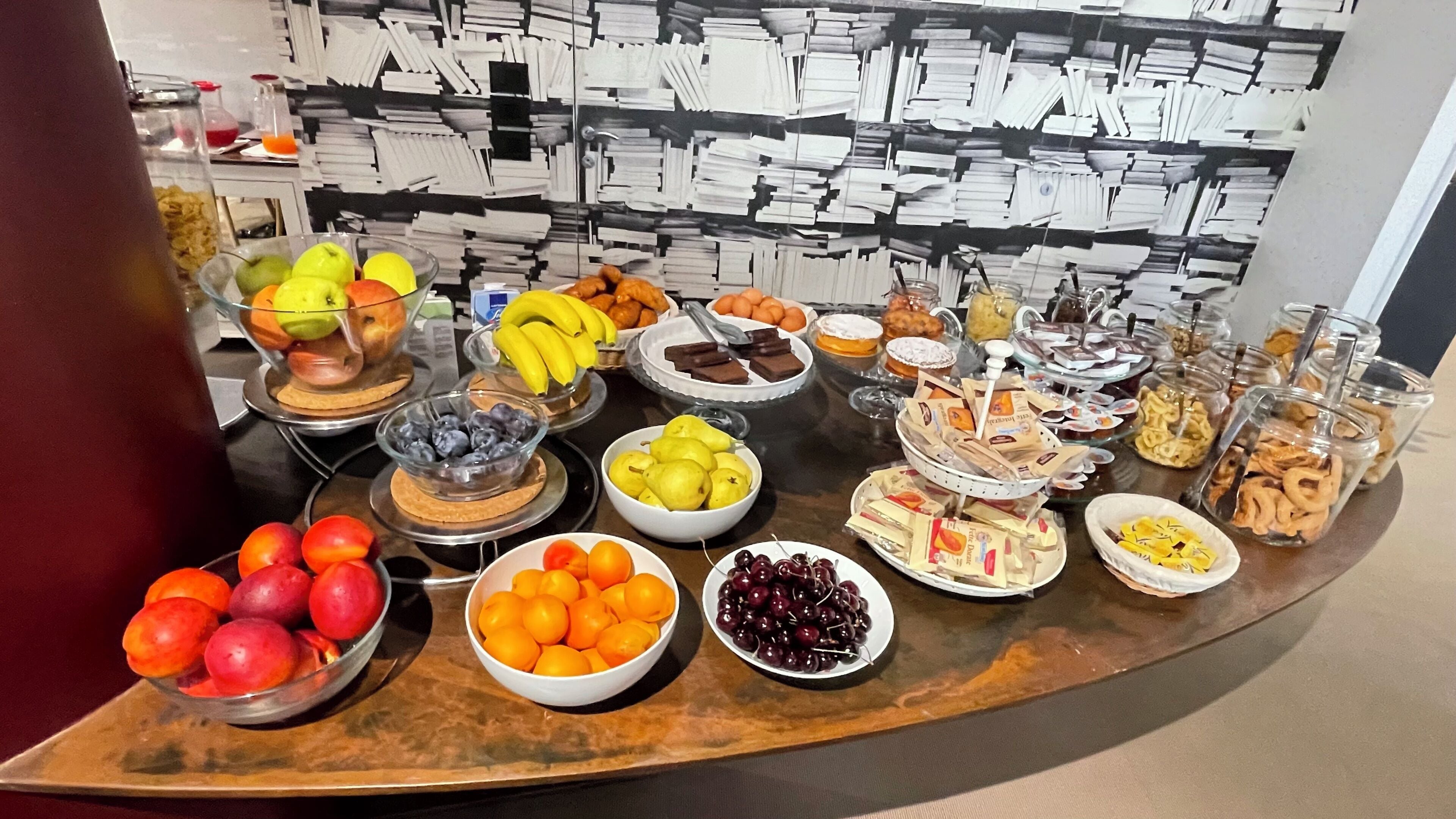 A buffet table with various fruits, pastries, and condiments.