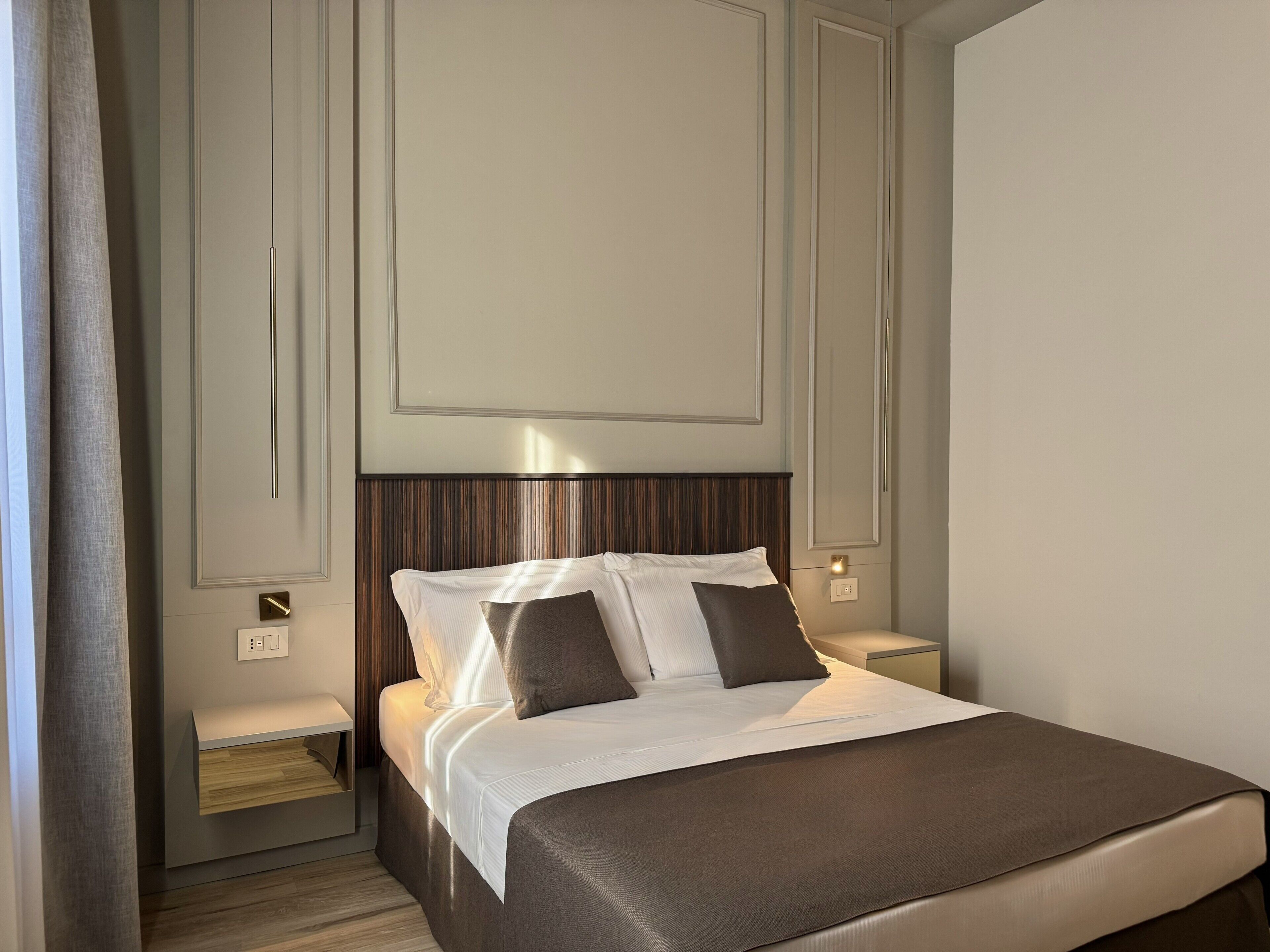 Una habitación de hotel con cama, mesitas de noche y un velador.