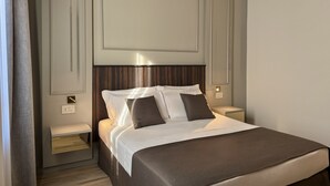 Hotellihuone, jossa on sänky, yöpöydät ja yölamppu.