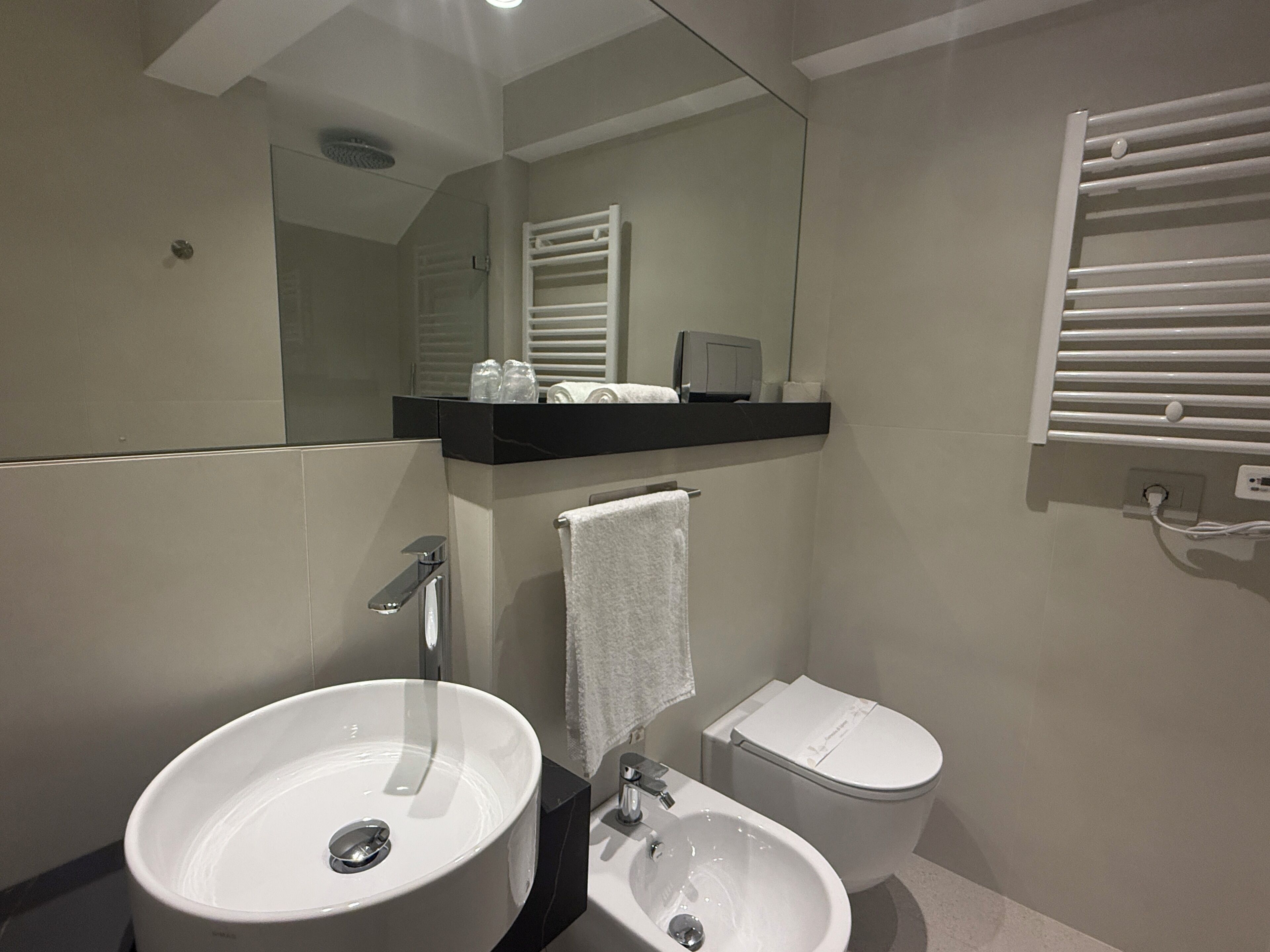 Ein modernes Badezimmer mit einem großen Waschbecken, einer Toilette und einem Handtuchhalter.