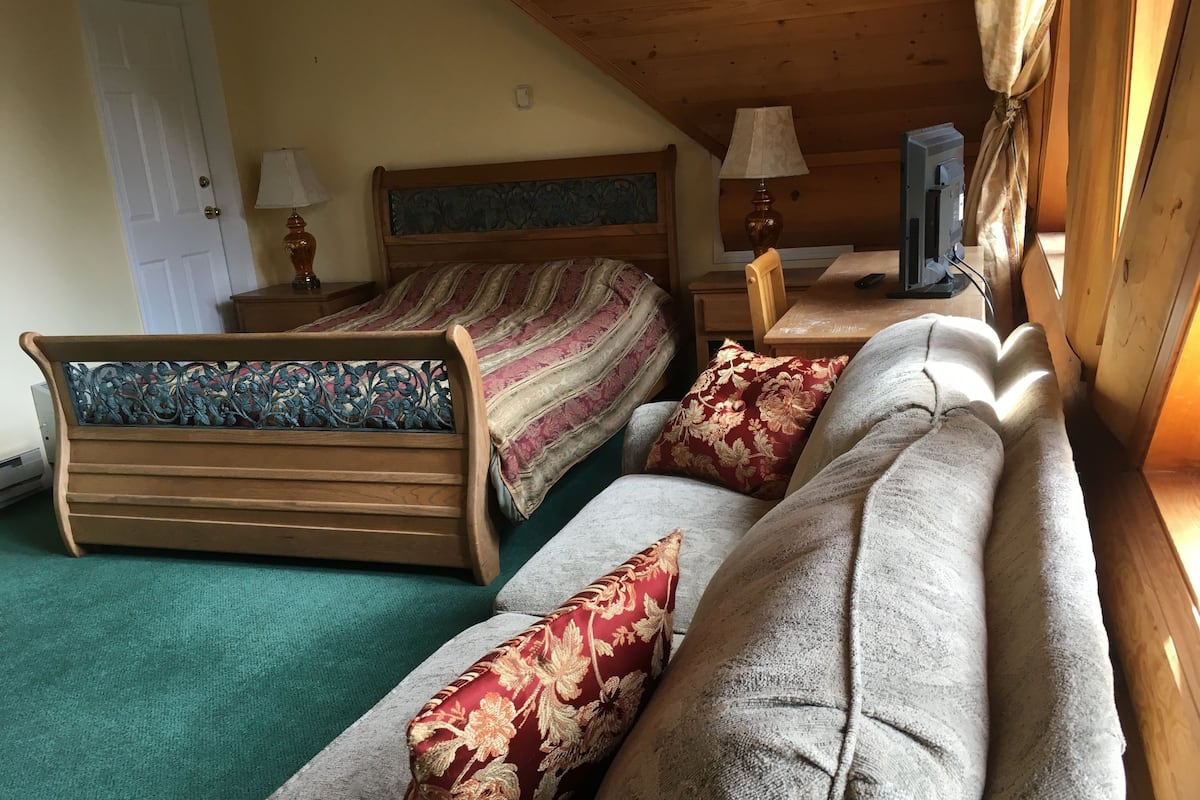 A cozy room with a bed, a sofa, and a table with lamps.