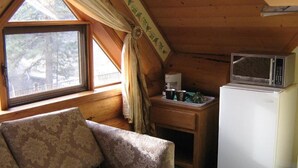 A cozy cabin with a wooden interior, a sofa, a small table with a microwave, and a refrigerator. - Rainbow Lake Castle Resort (Princeton)