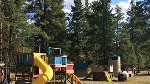A playground with a yellow slide and a castle-like structure. - Rainbow Lake Castle Resort (Princeton)