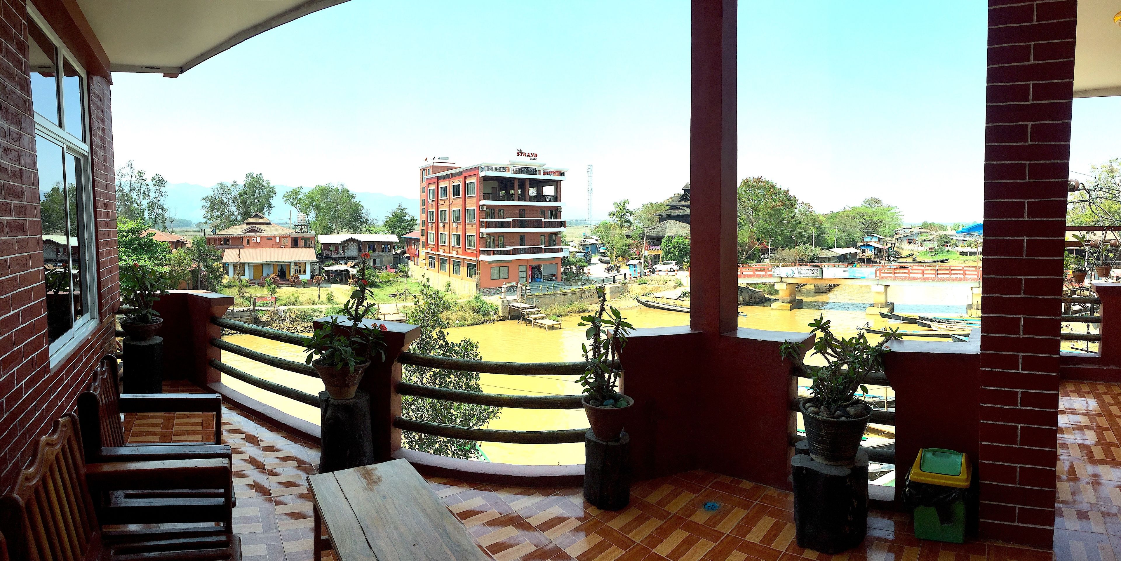 A balcony with a view of a town, potted plants, and a wooden bench.