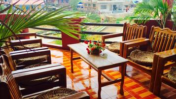 A terrace with wooden furniture, a tiled floor, and a view of the surrounding area.