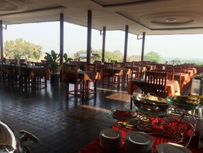 A restaurant with outdoor seating, tables with orange tablecloths, and a buffet with various food items. - Inle Star Hotel (Nyaungshwe)