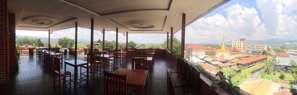 A restaurant with a terrace overlooking a cityscape, featuring a view of buildings and mountains. - Inle Star Hotel (Nyaungshwe)