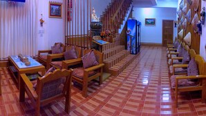 A traditional room with wooden furniture, a tiled floor, and a staircase leading to another level.