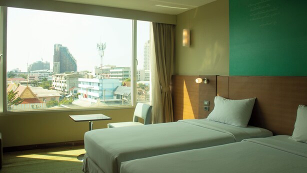 Une chambre d’hôtel avec deux lits, une petite table et une vue sur le paysage urbain.