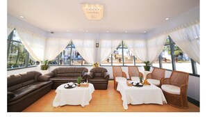 Una habitación amplia con un sofá grande, dos mesas de comedor y sillas de mimbre.