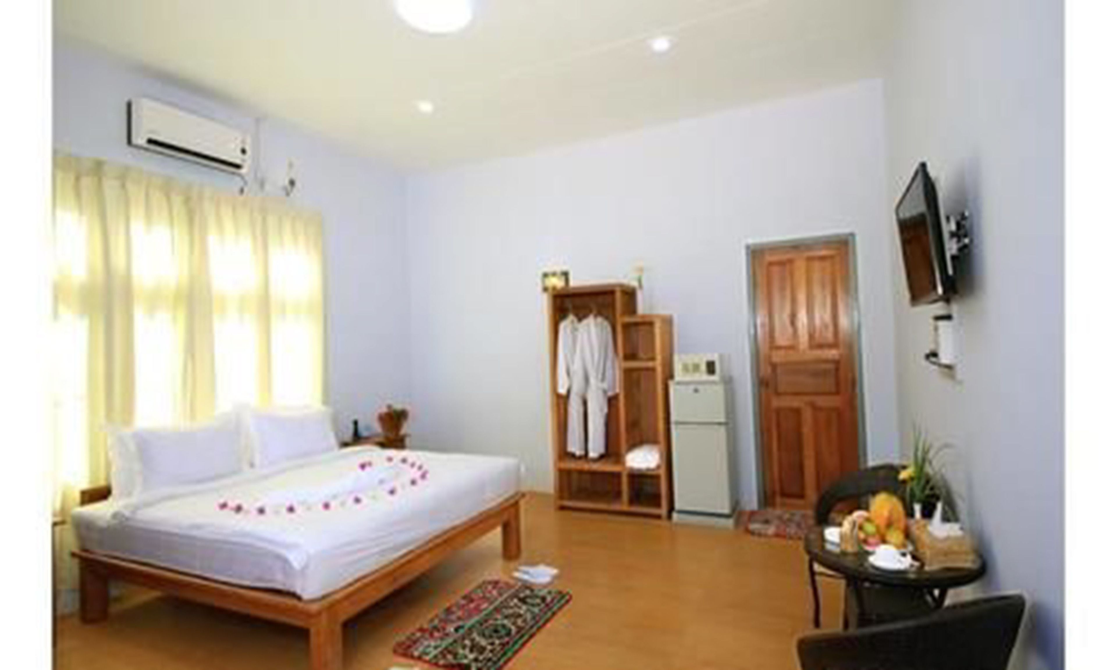 A bedroom with a bed, a desk, a chair, a wardrobe, and a television.