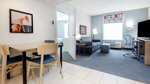A hotel room with a dining area, a sofa, a TV, and a window with a view. - Home2 Suites by Hilton Gillette (Gillette)