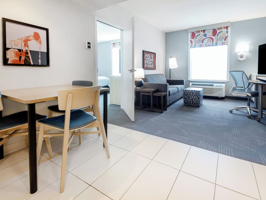 A hotel room with a dining area, a sofa, a TV, and a window with a view.
