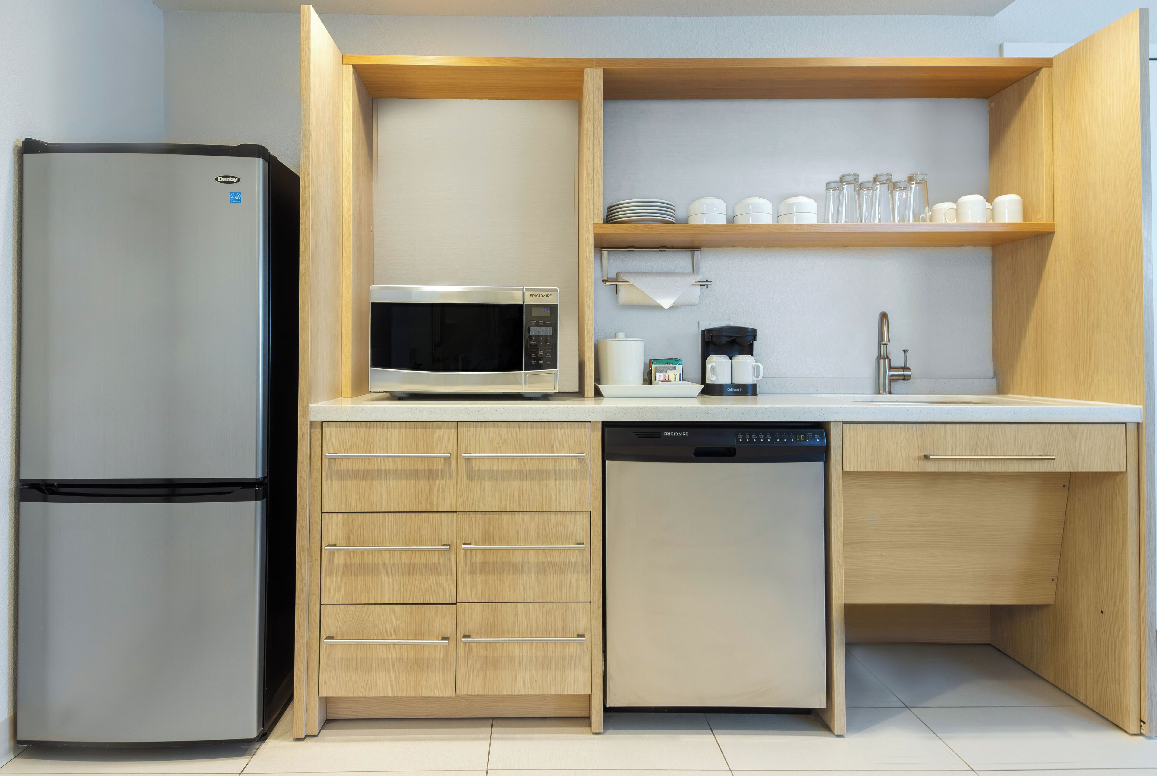 A compact kitchen with a refrigerator, microwave, coffee maker, and dishwasher.