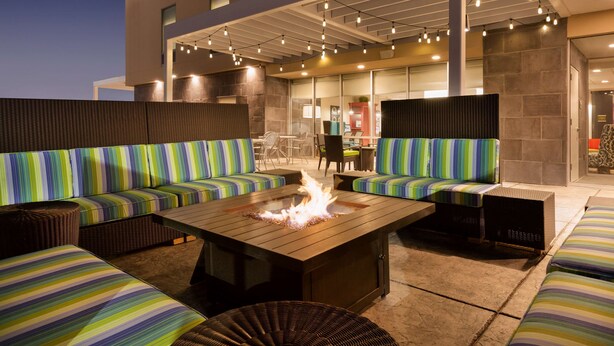 An outdoor seating area with striped sofas and a central fire feature. - Home2 Suites by Hilton Gillette (Gillette)