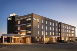A modern hotel building with multiple floors, large windows, and a well-lit entrance area. - Home2 Suites by Hilton Gillette (Gillette)