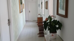 A hallway with white walls, a wooden bench, and a potted plant.