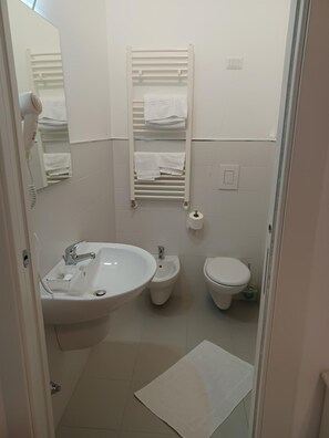 A small, clean bathroom with a sink, bidet, toilet, towel rack, and a mirror. - Hotel Costa (Bari)