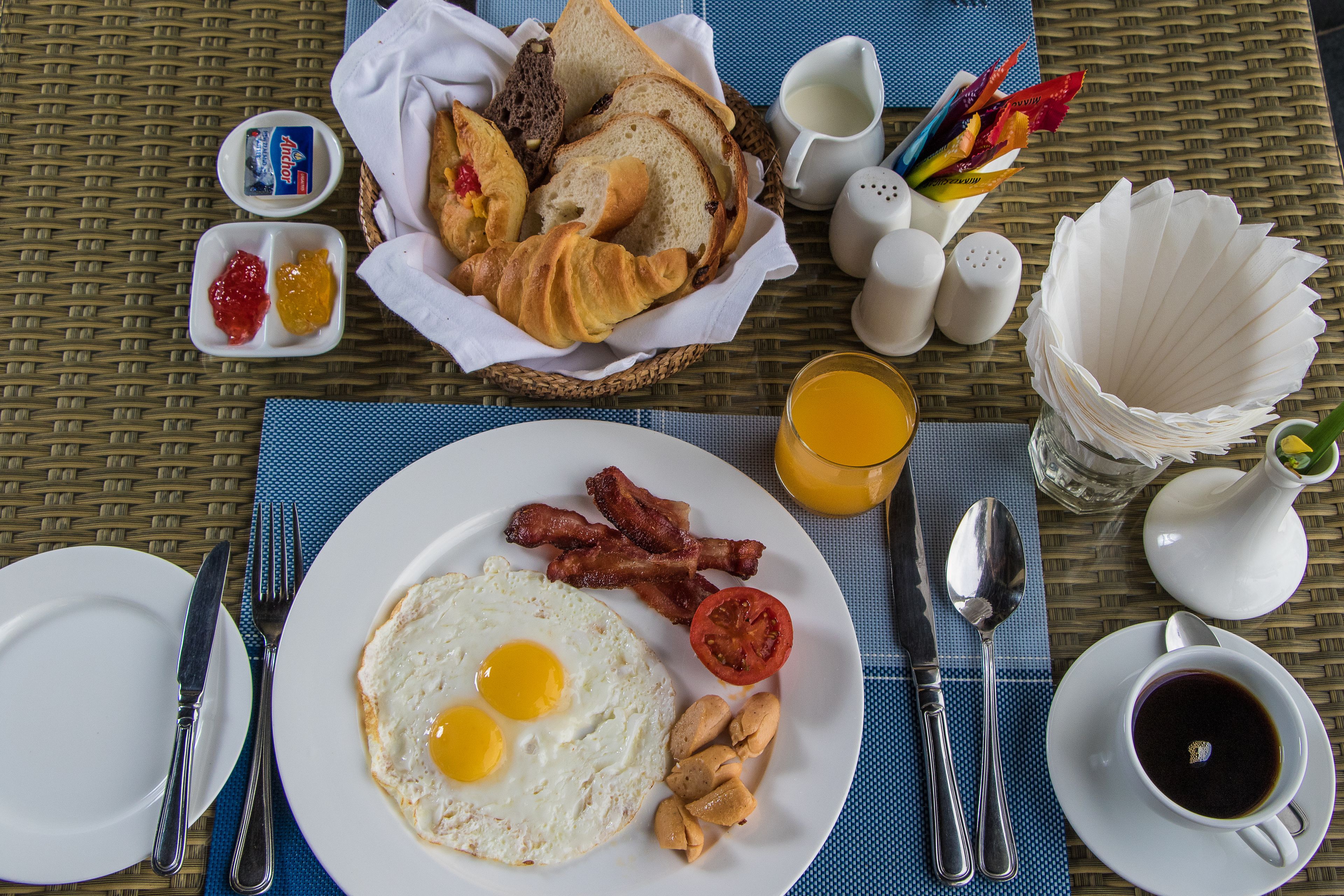 A breakfast table with eggs, bacon, toast, and jam.