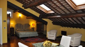 A cozy room with a bed, two chairs, a table with a vase of sunflowers, and a skylight above. - Piazza Nova Guest House (Ferrara)