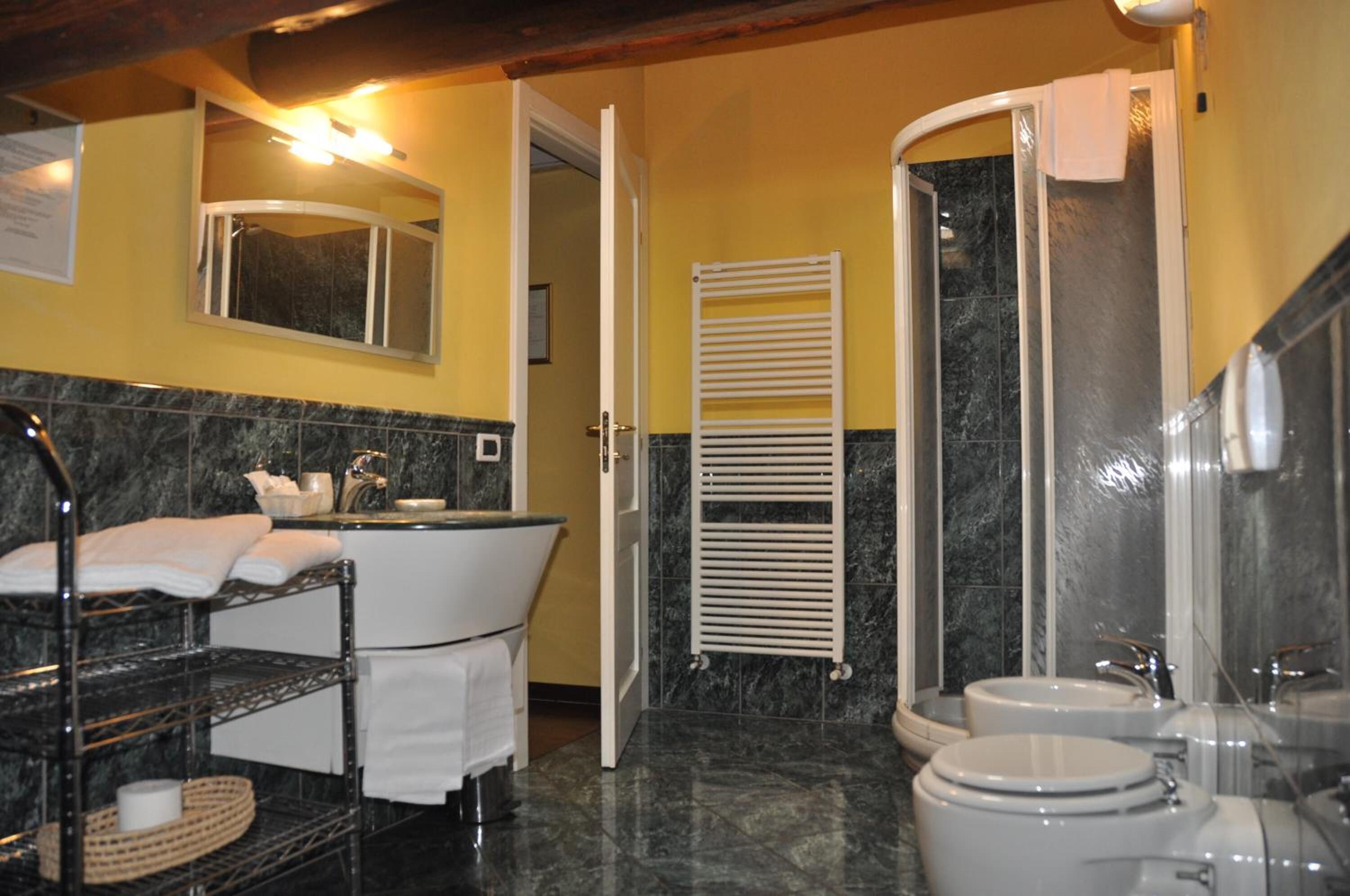 Un baño con bañera, dos lavamanos, inodoro, toallero y espejo.